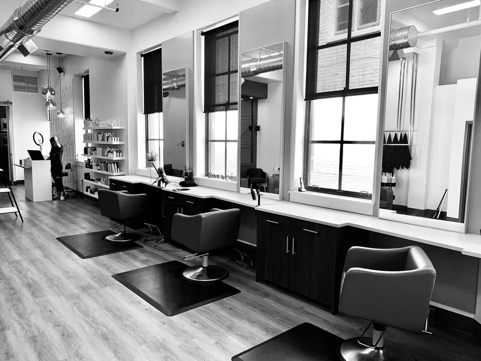 Bright, minimal beauty studio with black chairs and tall windows