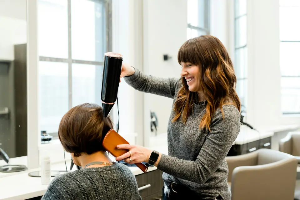 Stylist blow-drying a client's hair in a bright studio